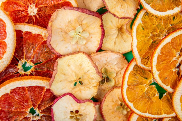 Background of dried fruits grapefruits apple and orange slices top view