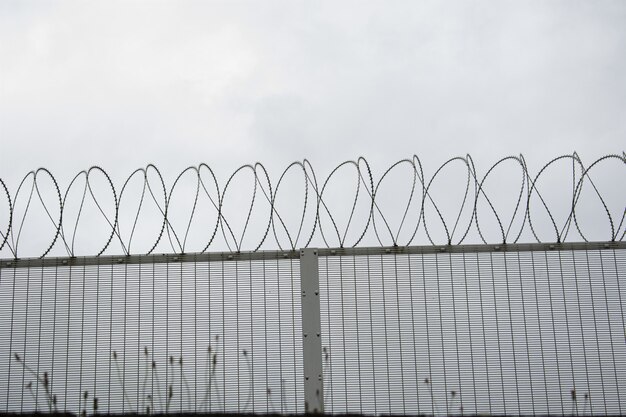 Background of a fence with barbed wires under a dark sky