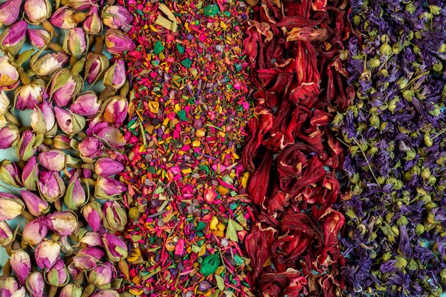 Background of mixed herbal tea blooms rose petals dried rose buds and herbs top view