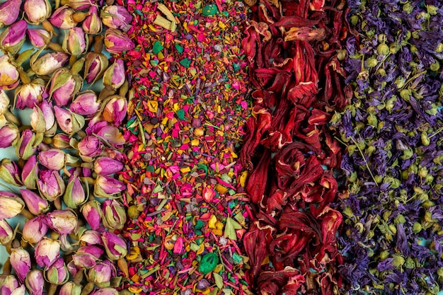 Background of mixed herbal tea blooms rose petals dried rose buds and herbs top view