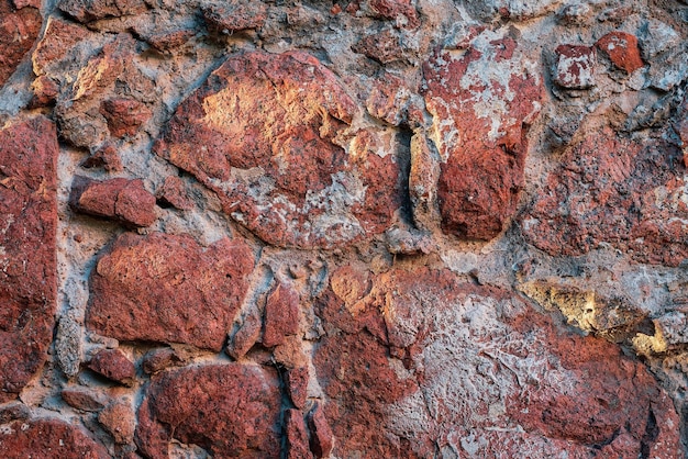 Background of red granite details of the old foundation of a medieval Scandinavian house from granite stones held together with mortar Natural background idea for interior or wallpaper