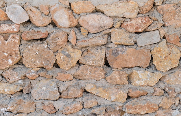 돌이 고르지 않은 오래된 벽의 배경에는 돌이 엉망으로 쌓여 있습니다. 복사 공간이 있는 배경 또는 벽지에 대한 빈티지 스타일 아이디어