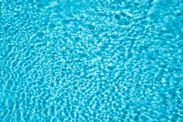 Background of swimming pool with water in sunlight blurred water background