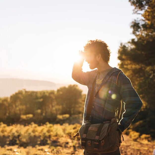 Backlit man using binoculars