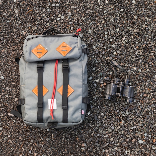 Backpack and binoculars on gravel