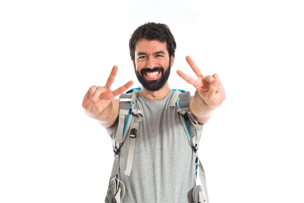 Backpacker doing victory gesture over white background