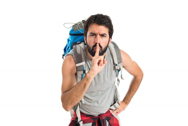 Backpacker making silence gesture over isolated white background