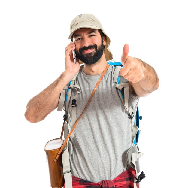 Backpacker говорить с мобильным на белом фоне