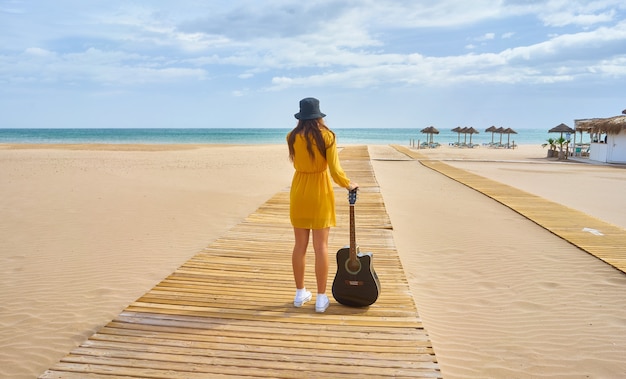 Backshot di un hipster in posa con una chitarra acustica