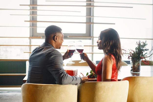 Заднее фото романтической черной пары, сидящей в ресторане в элегантной одежде
