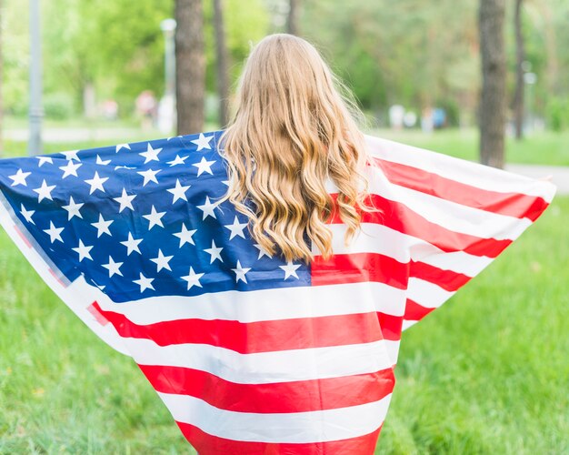 Backview girl with american flag in nature