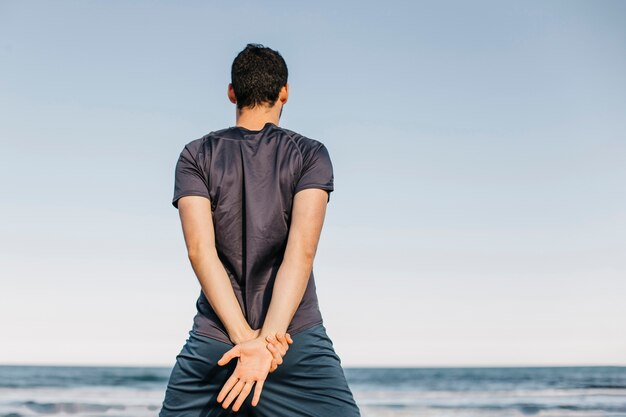 Backview of man stretching at the beach