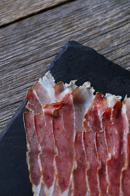 Free photo bacon on black stone plate, top view