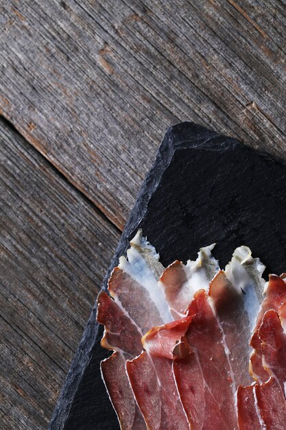 Bacon on black stone plate, top view