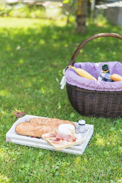베이컨; 푸른 잔디 위에 바구니와 쟁반에 치즈와 빵