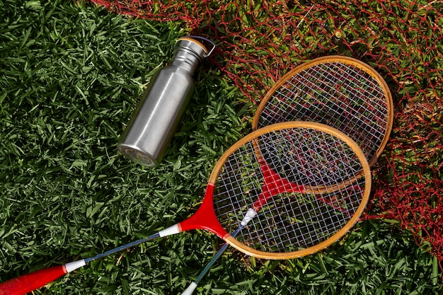 Free photo badminton rackets and flask on grass