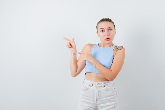 Baffled girl is showing something on left side on white background