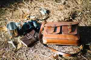 Free photo bag and binoculars on foliage