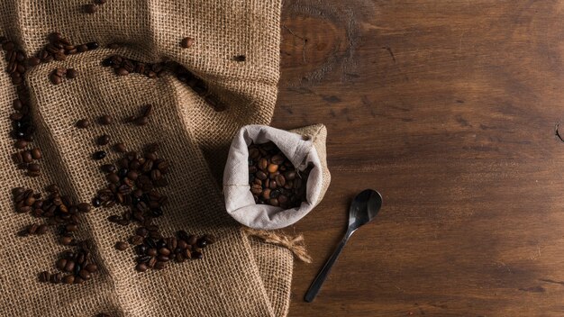 Bag with coffee and spoon near beans