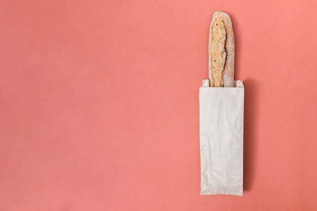 Baguette bread in the paper bag over the colored background