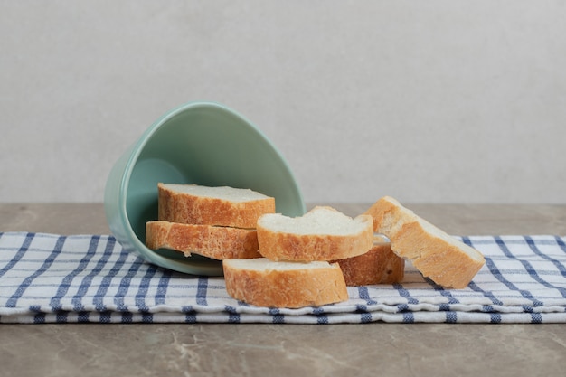 Fette di pane baguette dalla ciotola sulla tovaglia. foto di alta qualità