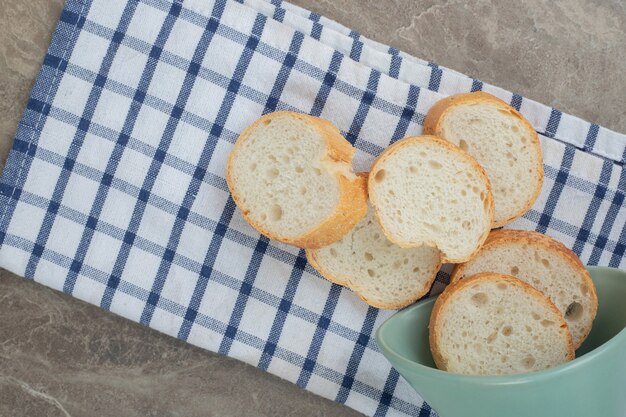 Бесплатное фото Ломтики хлеба багет из миски на скатерти. фото высокого качества