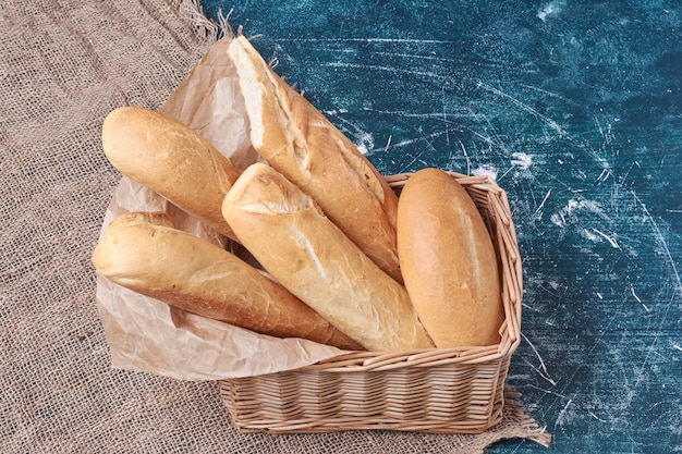 Free photo baguette breads in the bamboo basket on blue table.