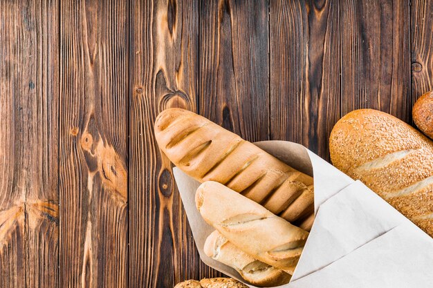 Baked baguettes wrapped in paper on wooden table