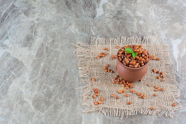 Fagioli al forno in una ciotola di argilla su un tovagliolo di tela, sul marmo.