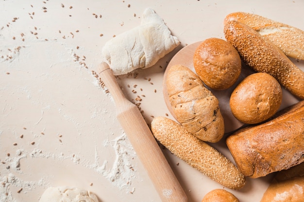 Baked breads with dough and rolling pin on backdrop