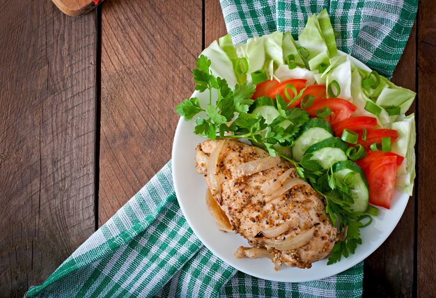 Запеченная куриная грудка и свежие овощи на тарелке