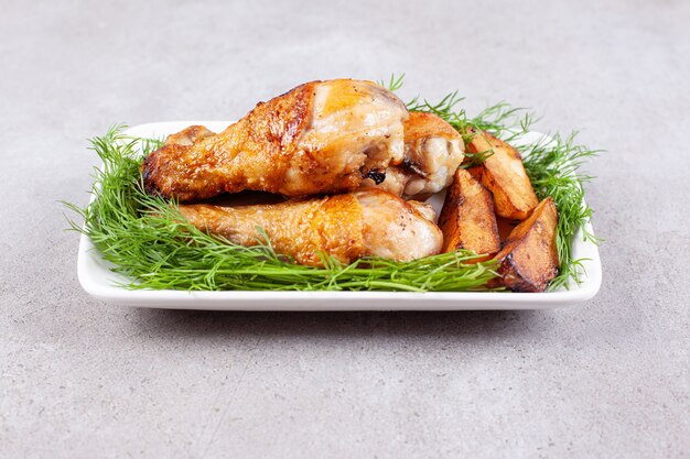 Baked chicken legs with greens on a white plate