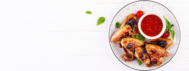 Baked chicken wings in the Asian style and tomatoes sauce on plate. Top view copyspace