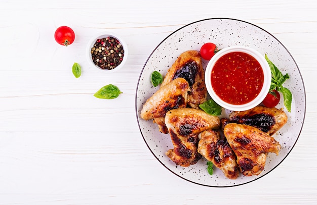 Baked chicken wings in the Asian style and tomatoes sauce on plate