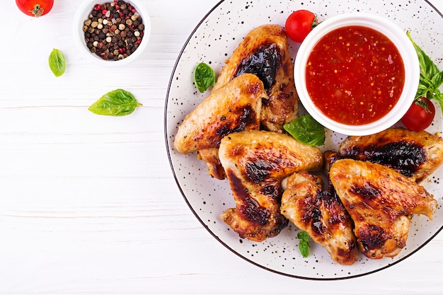 접시에 토마토 소스와 아시아 스타일의 구운 닭 날개