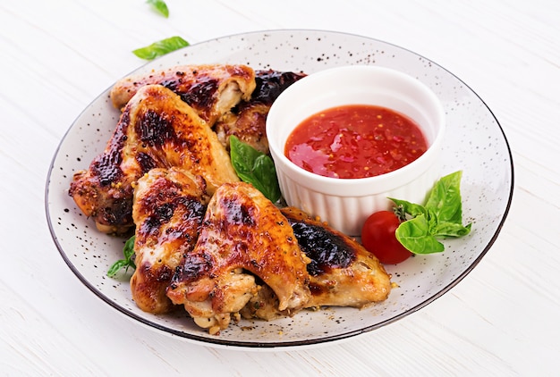 접시에 토마토 소스와 아시아 스타일의 구운 닭 날개