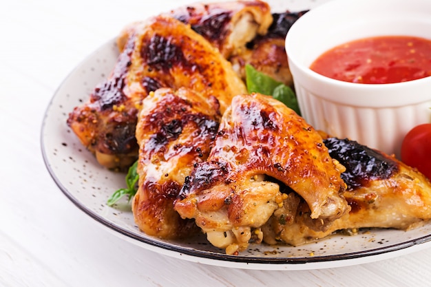 접시에 토마토 소스와 아시아 스타일에 구운 닭 날개.