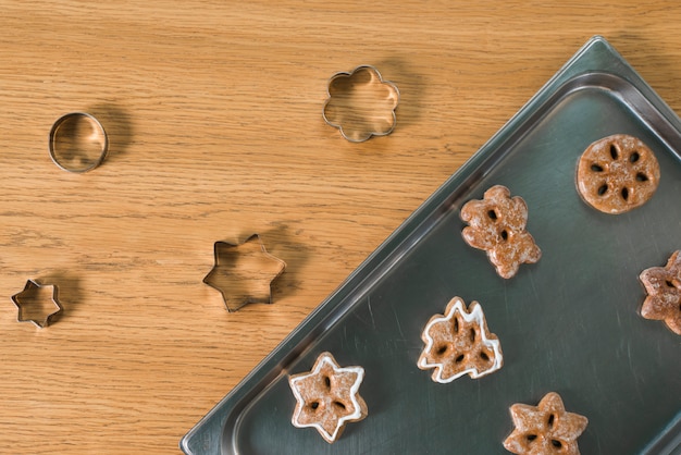Baked christmas cookies and pastry cutters on wooden table