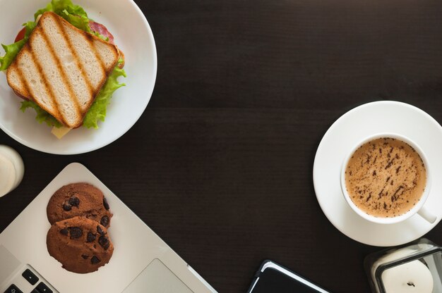 Baked cookies; sandwich; and coffee cup on black background