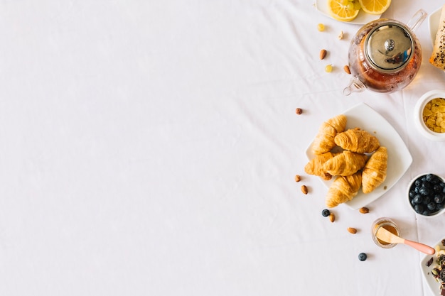 Baked croissant; fruits; tea and dryfruits on white background