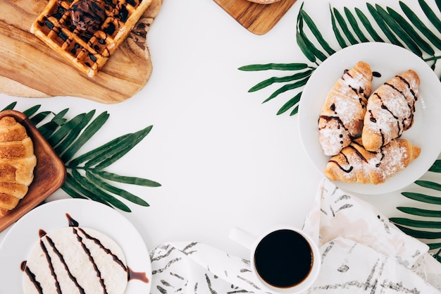 Baked croissant; waffles; buns; tortillas and coffee on white backdrop