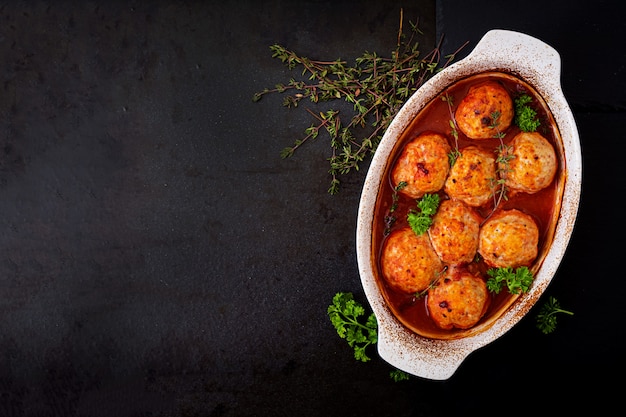 Baked meatballs of chicken fillet in tomato sauce.