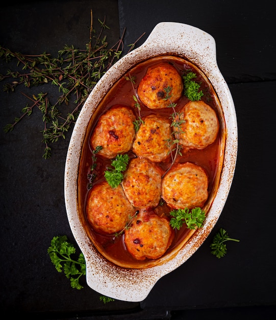 Baked meatballs of chicken fillet in tomato sauce.