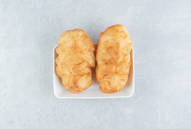 Baked piroshki with potatoes in white bowl. 