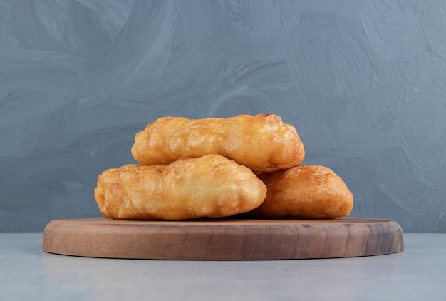 Baked piroshki with potatoes on wooden board.