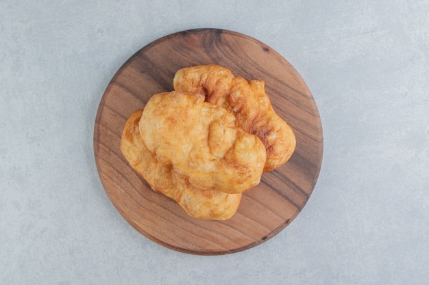 Baked piroshki with potatoes on wooden board.