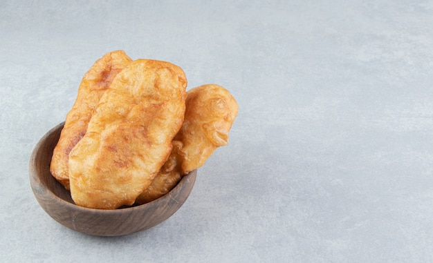 Baked piroshki with potatoes in wooden bowl. 