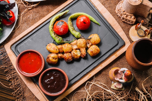 Бесплатное фото Запеченный картофель на деревянной доске с перцем томатный соусы вид сверху