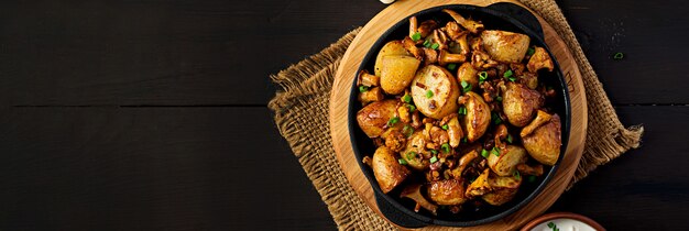 Baked potatoes with garlic, herbs and fried chanterelles in a cast iron skillet. Top view