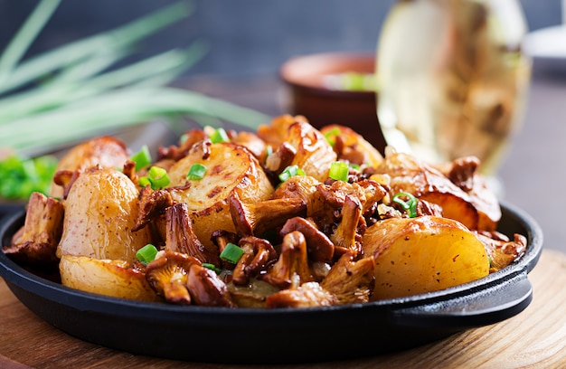 Baked potatoes with garlic, herbs and fried chanterelles in a cast iron skillet.